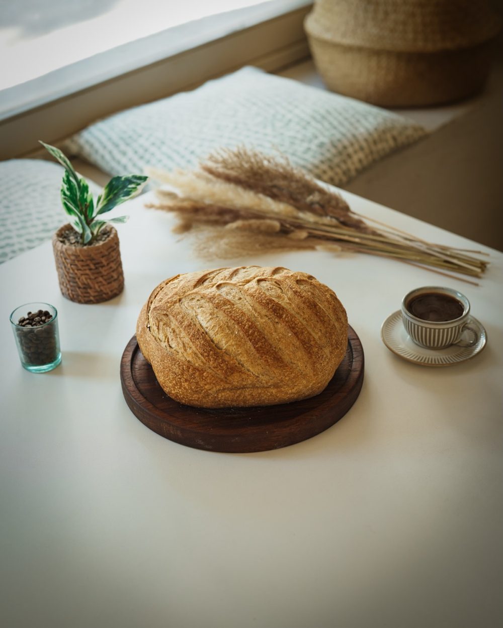 Hogaza de masa madre junto a espigas de trigo y un café